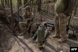 Ukrainian soldiers from the Skala regiment artillery unit wait next to shells as their fellow soldiers fire an M109 howitzer toward Russian positions in the eastern Donetsk region on April 23.