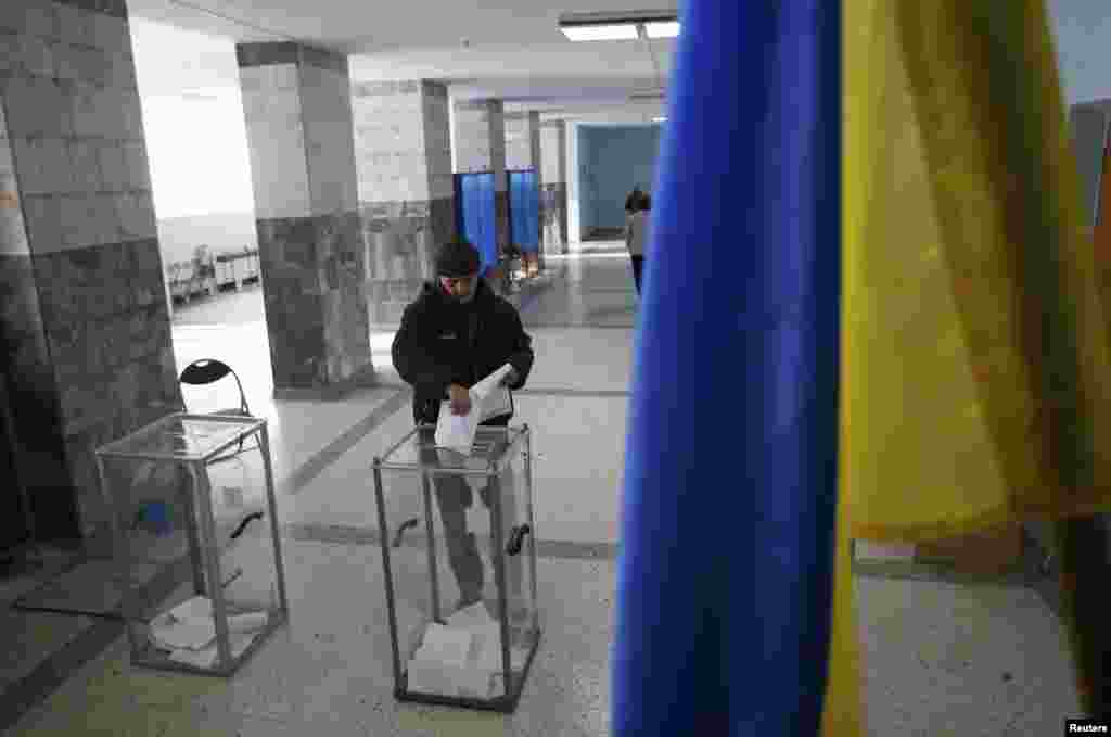 Украинаның шығысындағы сайлау учаскесінде парламент сайлауына дауыс беріп жатқан адам. Волноваха кенті, Донецк облысы, 26 қазан 2014 жыл.