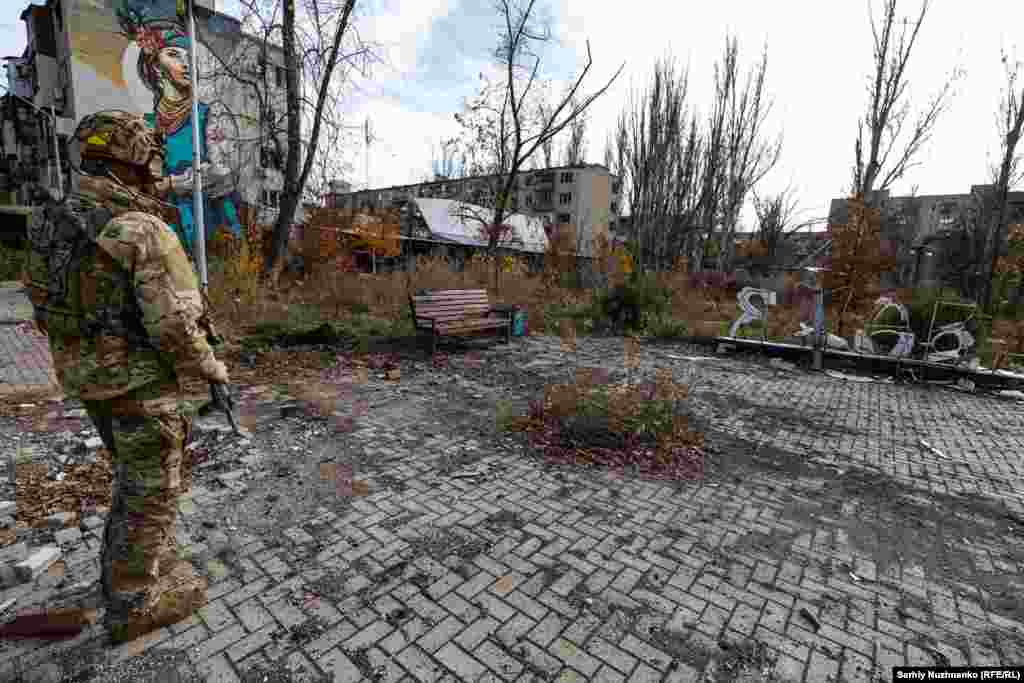 Украинский военный в Авдеевке возле поврежденной металлоконструкции &laquo;Я люблю Авдеевку&raquo;, ноябрь 2023 года. В это время фотокорреспондент Украинской редакции Азаттыка Сергей Нужненко побывал в городе в последний раз перед оккупацией. Российская армия захватила Авдеевку в феврале 2024 года. Сражения за город продолжались более пяти месяцев&nbsp;