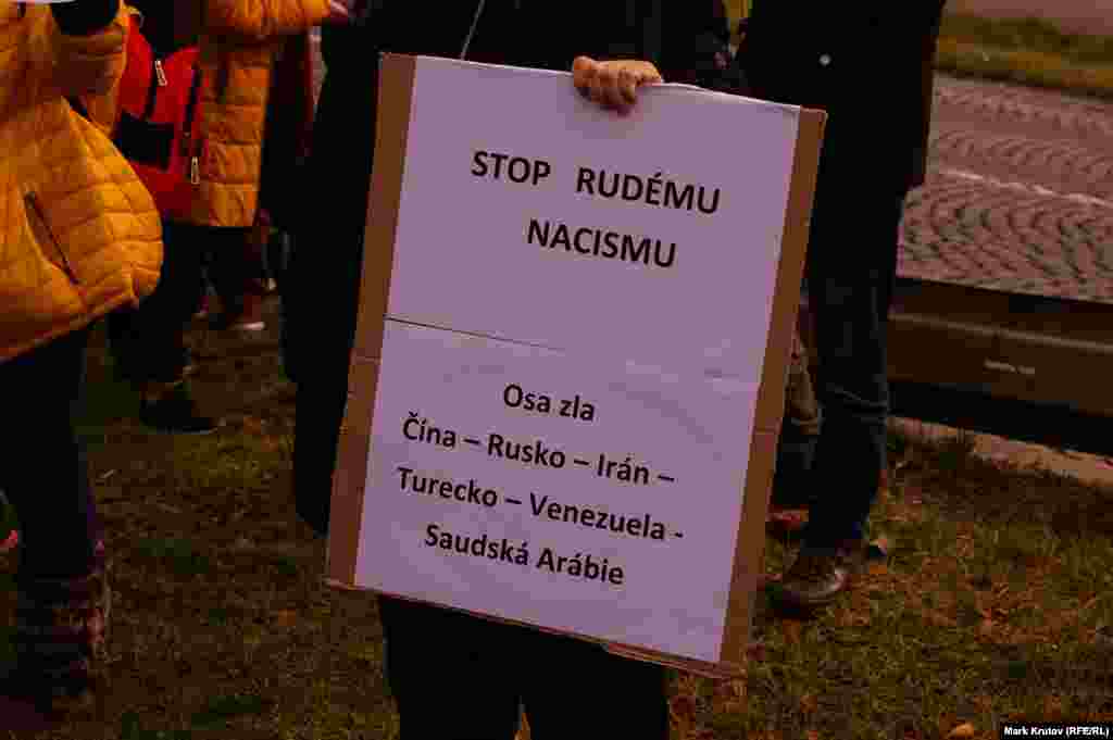 Плакат в руках одного из пришедших на церемонию: "Остановить красный нацизм. Ось зла: Китай – Россия – Иран – Турция – Венесуэла – Саудовская Аравия".