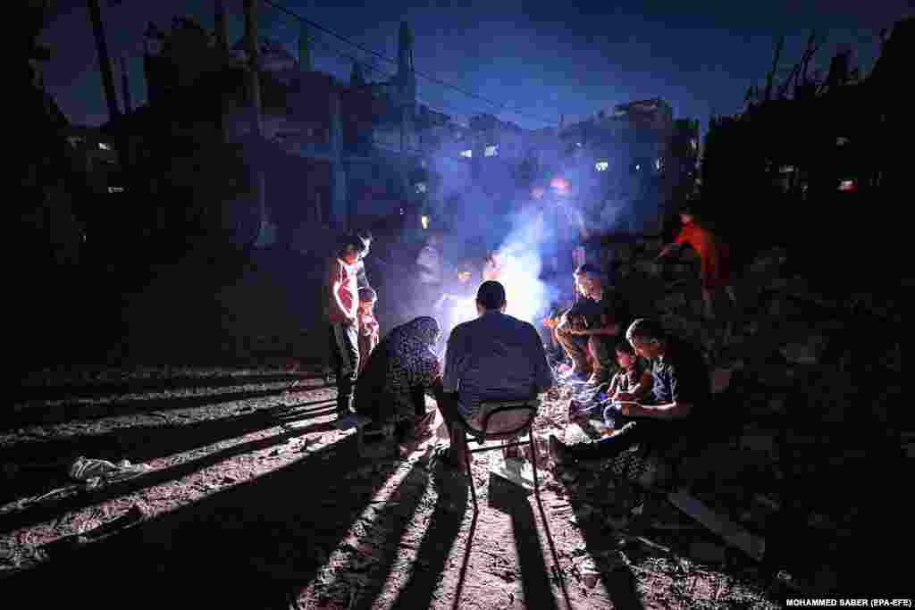 Palestinezët mblidhen rreth një zjarri së bashku me familjet e tyre, në Beit Hanun më 26 maj, 2021.
