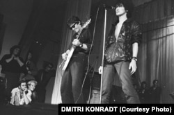 Viktor Coj (jobb oldalon) és a Kino fellépése 1987-ben a Leningrádi Rock Klubban, miközben őket nézi a helyi zenei élet két kulcsfigurája, Joanna Stingray és Borisz Grebenscsikov (balra lent). Coj lett az orosz popzene történetének egyik legikonikusabb alakja. Autóbalesetben vesztette életét 1990-ben, de azóta is legendaként él tovább a volt Szovjetunió utódállamaiban. A nyugati fiatalok is hallották a zenéjét – még ha nem is tudnak róla. A Grand Theft Auto videójátékban szóló fiktív Vladivostok FM rádió egyik száma a Kino klasszikus dala a Gruppa Krovji (Vércsoport). A számot a licenc lejárta után, 2018-ban kivették a játékból.