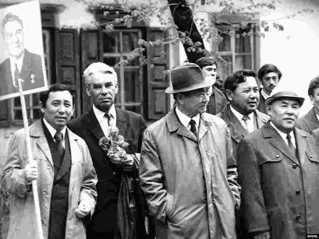 Каришал Асанов (слева) с портретом первого секретаря ЦК Компартии Казахстана Динмухамеда Кунаева в окружении ученых. - По собственному признанию, был случайно запечатлен фотографом в момент, когда один из его коллег попросил поддержать портрет Кунаева. Однажды неугомонный Каришал Асанов бросил вызов первому секретарю Центрального комитета Коммунистической партии Казахстана. Он пишет письмо на имя генерального секретаря ЦК КПСС Леонида Брежнева. Динмухамед Кунаев как раз в это время стал членом Политбюро и получил свою первую медаль Героя Социалистического Труда. Это был 1972 год, разгар застоя.