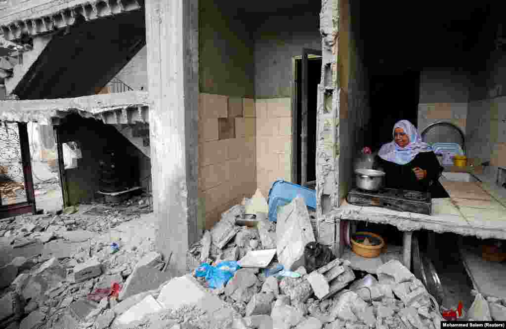 Kjo grua palestineze gatuan në kuzhinën e shtëpisë së saj të shkatërruar në Gaza. 23 maj, 2021.