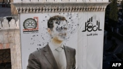 A megbukott és elmenekült szíriai vezető, Bassár el-Aszad szétlőtt portréja Hamá városában