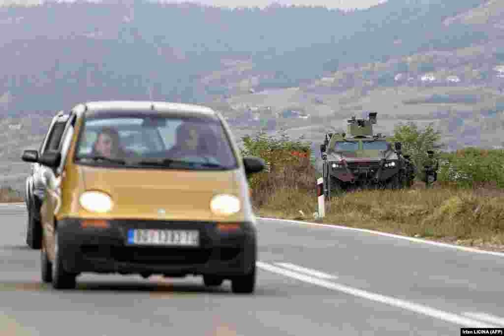 Automjete duke lëvizur nëpër një rrugë, pranë një autoblinde të ushtrisë serbe, në Rudnicë. (27 shtator)