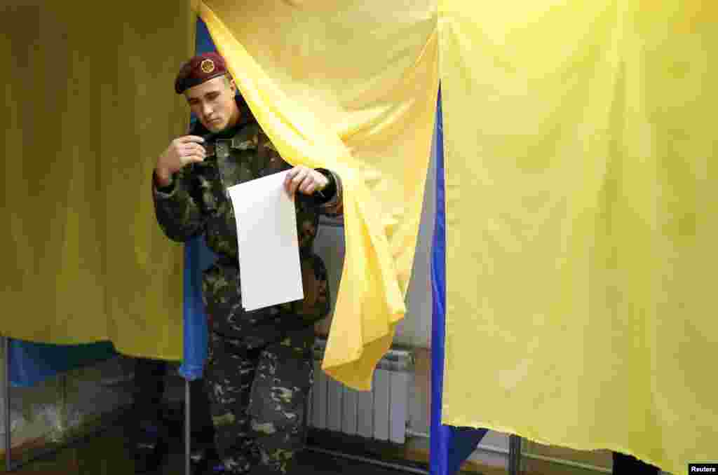 Сайлау бюллетеніне өз қалауы туралы белгі салып болған соң, оны сайлау жәшігіне салуға келе жатқан әскери қызметші. Киев, 26 қазан 2014 жыл.