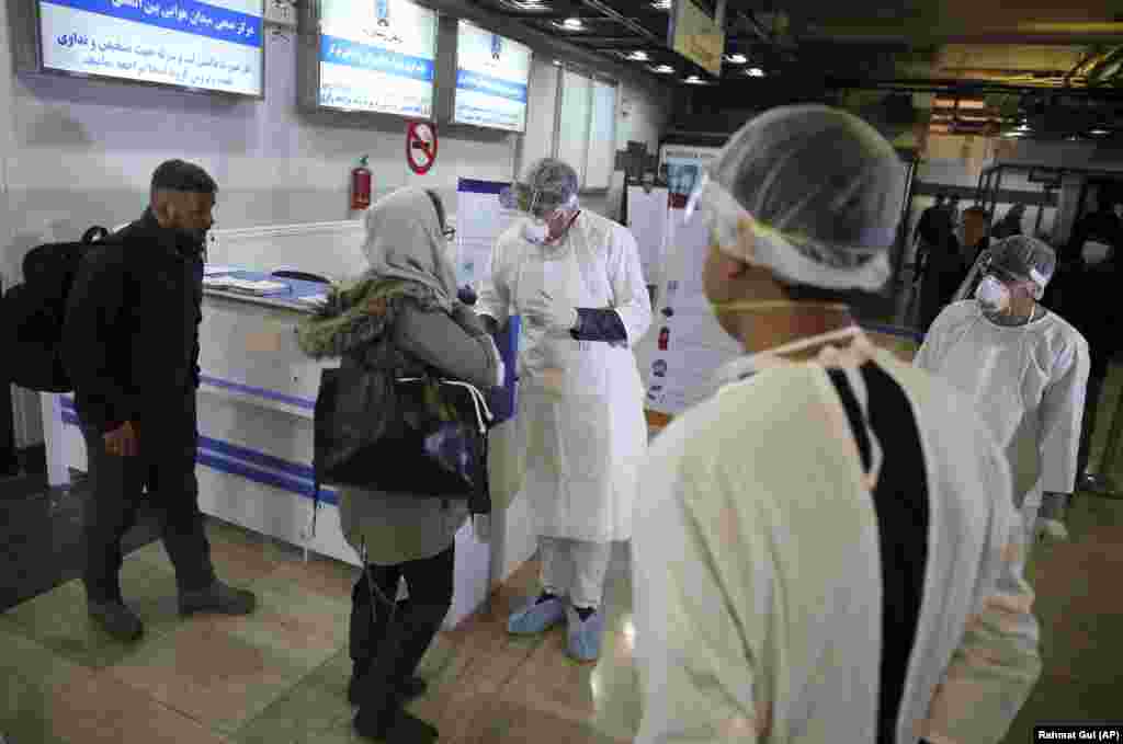 Afghan health-care workers speak with passengers who had just arrived from China at the airport in Kabul.
