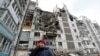 A local resident reacts next to the building where her destroyed apartment is located in the besieged city of Mariupol