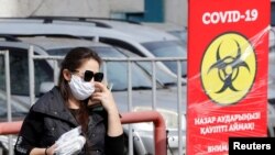 Женщина в защитной маске у пункта тестирования в Алматы во время пандемии нового коронавируса.