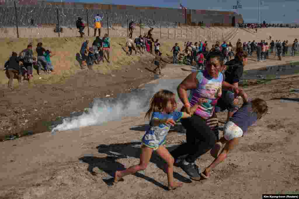 Maria Meza, o migrantă de 40 de ani din Honduras, alegând cu fiicele ei de cinci ani de gaze lacrimogene lângă zidul de la granița dintre SUA și Mexico. Tijuana, Mexico, 25 noiembrie 2018.(Reuters/ Kim Kyung-hoon)