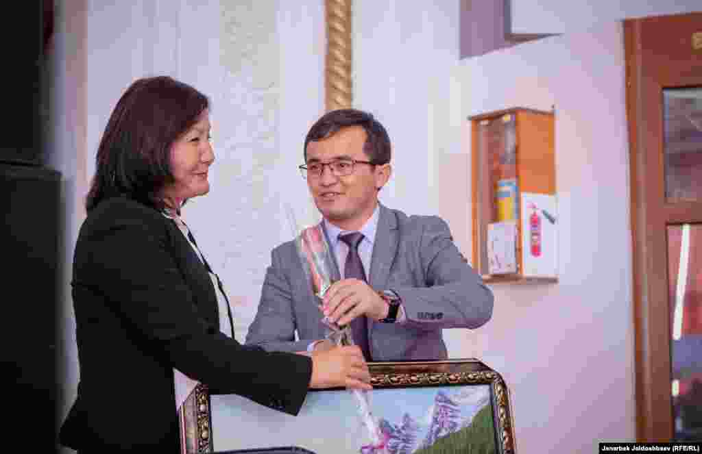 Ош мэриясынын басма сөз кызматынын башчысы Азамат Апсаттаров "Азаттыктын" жетекчиси Венера Жуматаевага белек тапшырып жатат. 