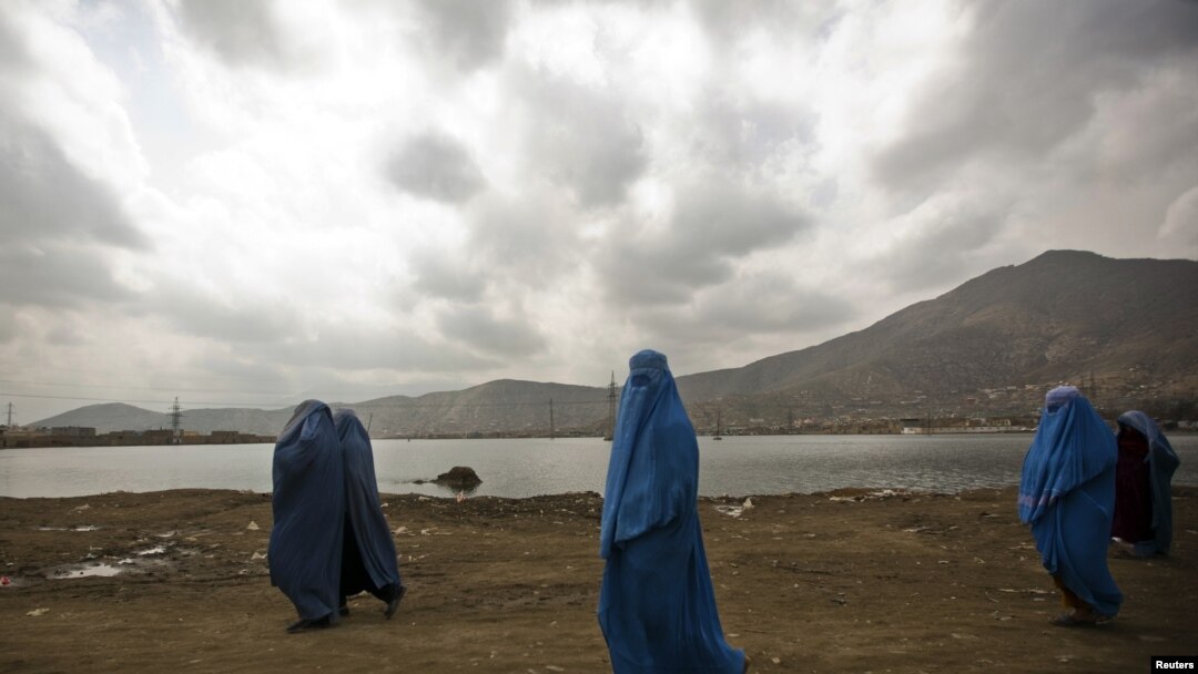 Burqa-clad women walk along a road in Kabul, where women continue to struggle for their rights.